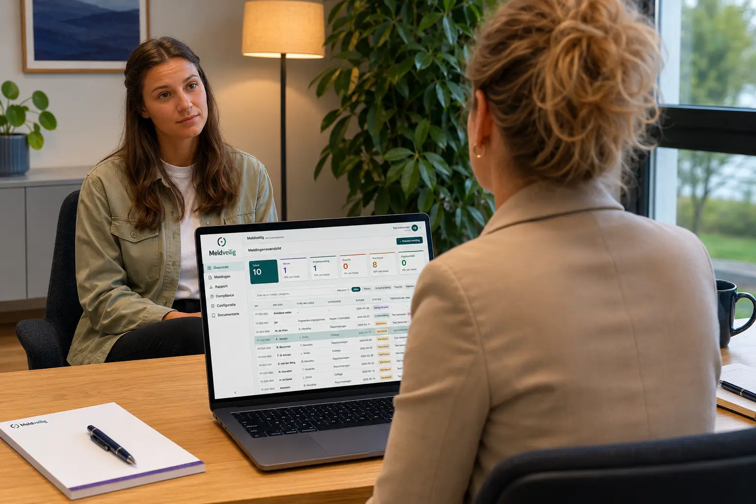 Vertrouwenspersoon in gesprek met een medewerker, met het Meldveilig-dashboard op de laptop